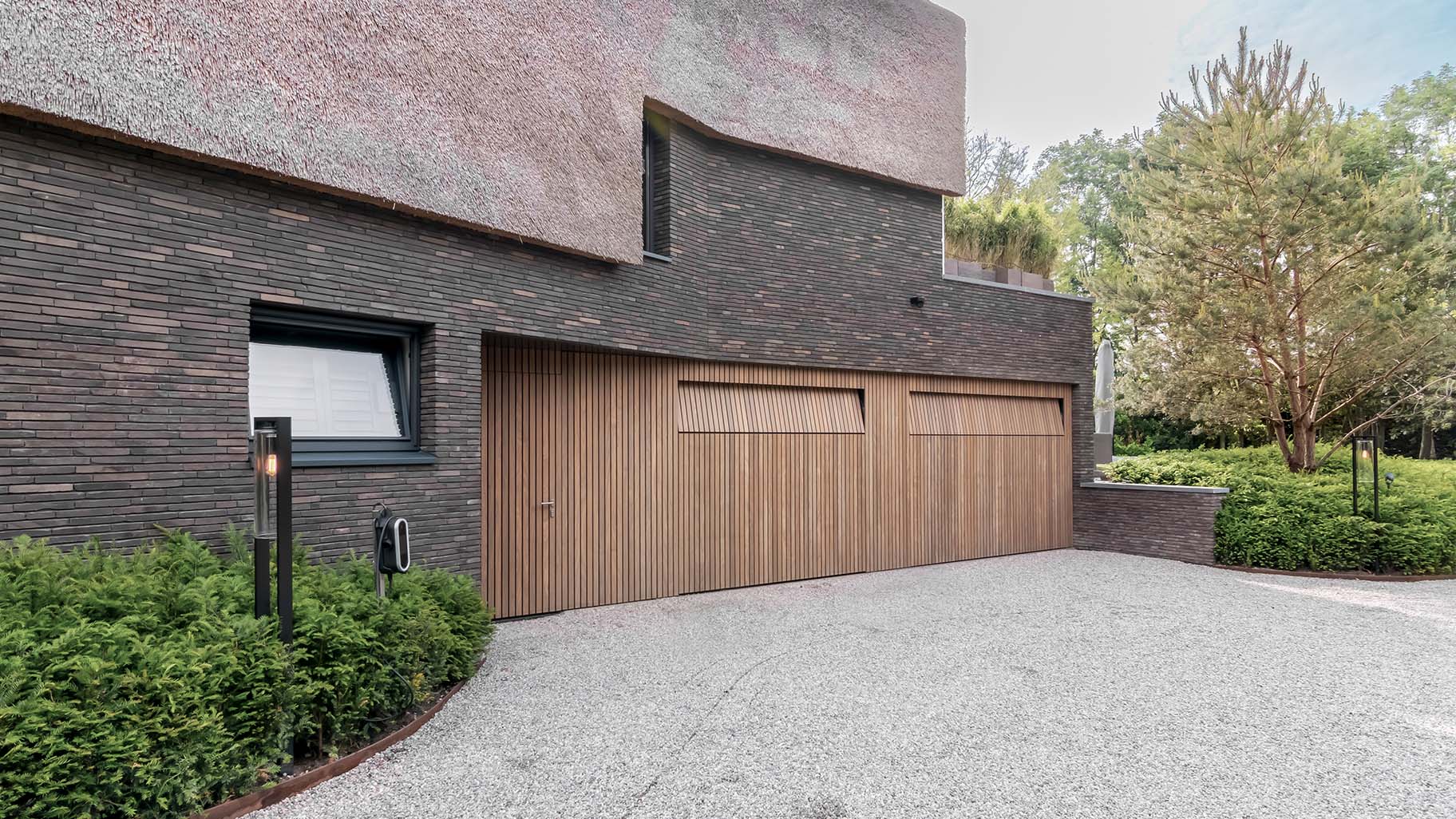 Afrormosia houten garagedeuren en loopdeur gelijk met de gevel