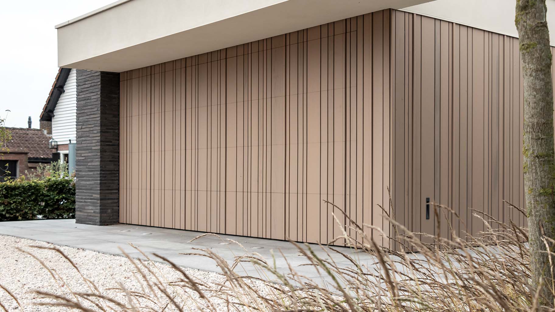 Houten garagedeur met verticale latten die gelijk met de gevel is geplaatst