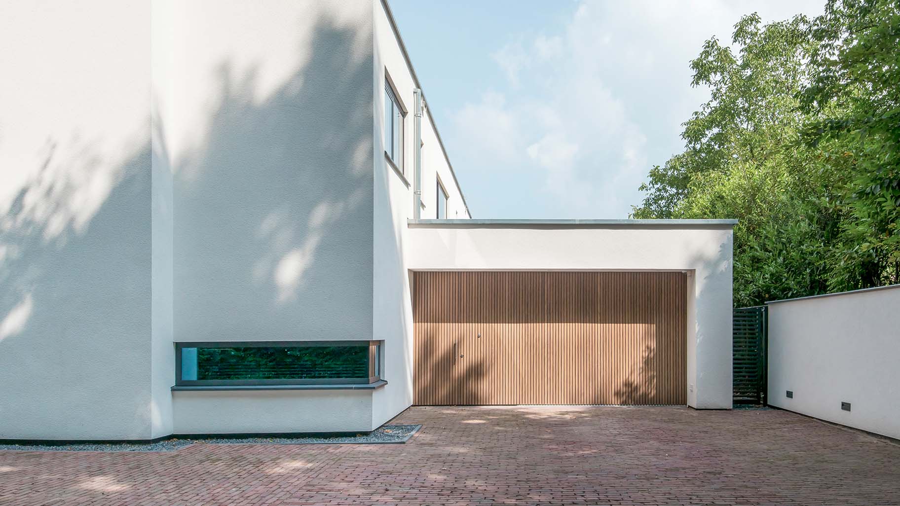 Moderne villa met Afrormosia houten zijwaartse sectionaaldeur en bijpassende voordeur