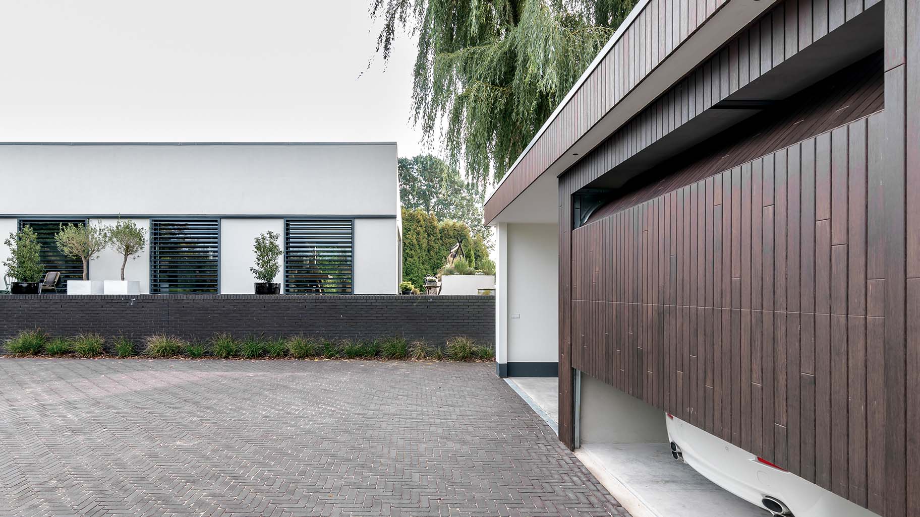 Carport met verticale sectionaaldeur van bamboe hout die een warme uitstraling